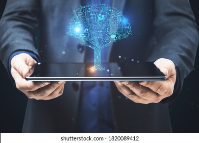 Businessman holding digital tablet with circuit tree hologram. Software and technology concept. - Powered by Shutterstock - Get 15% off with code: PIKWIZARD15