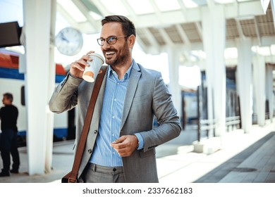 Businessman holding a disposable coffee cup at the train station platform. A man in a train station commuting to work. Businessman with coffee cup. Business person is waiting for train 