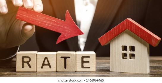 Businessman holding the down arrow on wooden blocks with the word Rate and house. Low interest in mortgages. Reducing interest payments for mortgage. The fall in housing rates on credit.