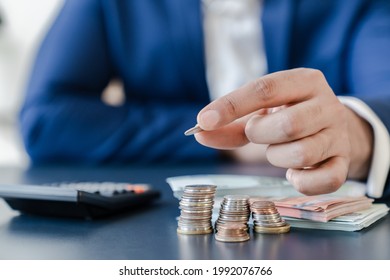 Businessman holding euro cents coins dollar bills on table with pile of coins and banks calculator, managing dividing money to save and invest it to make income. Saving money and investing concept.