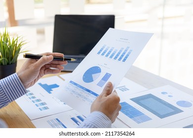 Businessman Holding Financial Documents, He Owns A Startup Company, He Sits Checking The Company's Financial Summary Prepared By The Finance Department. Management Concept Of Startup Company.