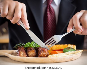 Businessman holding fork and knife eating steak, business and food/restaurant concept