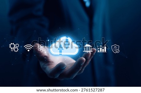 Businessman holding glowing cloud computing icon with fintech, analytics, and cybersecurity symbols, representing data transfer, digital transformation, secure enterprise network technology solutions.