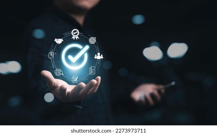 Businessman holding glowing correct sign mark with quality icon for quality assurance guarantee product and ISO service concept. - Shutterstock ID 2273973711