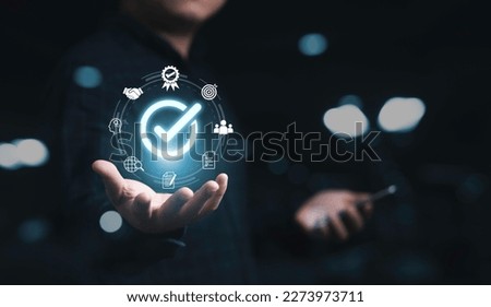 Businessman holding glowing correct sign mark with quality icon for quality assurance guarantee product and ISO service concept. 商業照片 © 