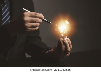 Businessman holding glowing lamp, Creative new idea. Innovation, brainstorming, strategizing to make the business grow and be profitable. Concept execution, strategy planning and profit management. - Shutterstock ID 2311063625