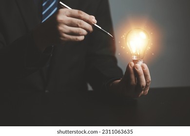 Businessman holding glowing lamp, Creative new idea. Innovation, brainstorming, strategizing to make the business grow and be profitable. Concept execution, strategy planning and profit management. - Shutterstock ID 2311063635