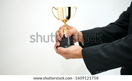 Businessman holding a golden trophy                                