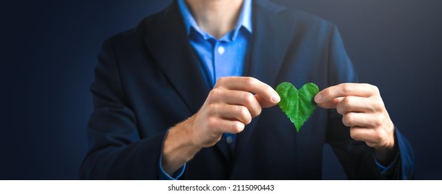 Businessman holding a green heart leaf. Company corporate social responsibility and environmental concern. Environmental and Ecology Care Concept.  - Shutterstock ID 2115090443