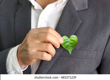 Businessman holding a green heart leaf / Business with corporate social responsibility and environmental concern                               