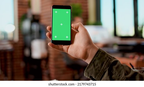 Businessman Holding Greenscreen Display On Mobile Phone, Analyzing Blank Mockup Template With Isolated Copyspace. Modern Smartphone With Chroma Key Background Screen Used In Startup Office.