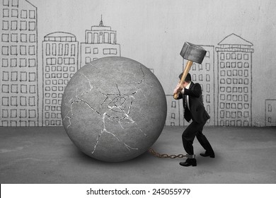 businessman holding hammer hitting cracked concrete ball with city buildings doodles background