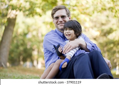 Businessman holding his disabled son on grass