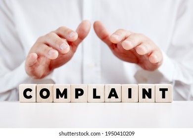Businessman holding his hands over the wooden cubes with the word complaint. Customer complaints support or care concept. - Shutterstock ID 1950410209