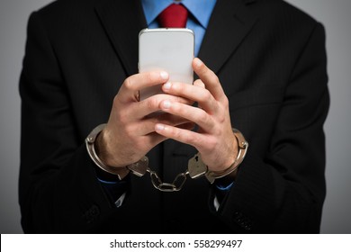 Businessman Holding His Phone With Handcuffs, Technology Slave Concept