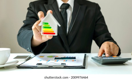 Businessman Holding A House Model With Energy-saving And Clean Energy Chart, Energy-saving Concept, Energy Efficiency Assessment In A Residential Home.