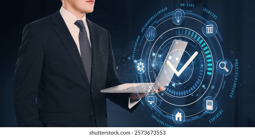 Businessman holding laptop, digital interface with holographic checkmark and icons, dark background. Concept of technology and approval