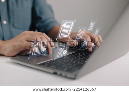 Businessman holding a laptop with a document management icon in it while utilizing the data system for business on the internet.