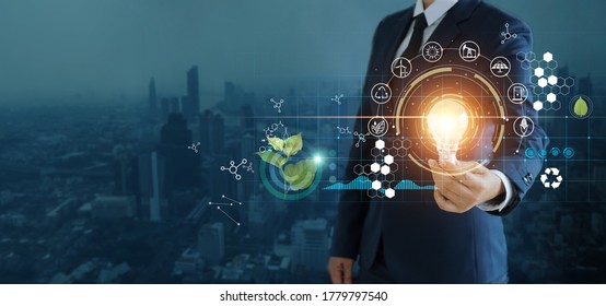 businessman holding light bulb against nature on city background  with icons energy sources for renewable, sustainable development,  Ecology and renewable energy concept.