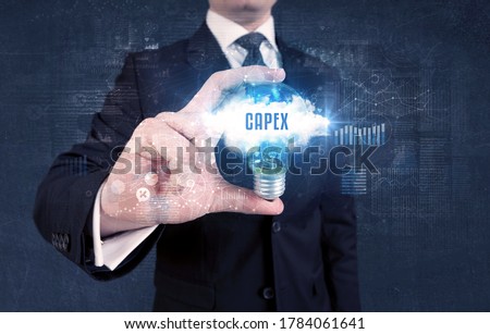 Businessman holding a light bulb with CAPEX inscription, new business concept