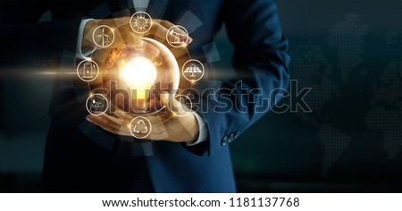 Businessman holding light bulb with energy sources icon. Campaigning for ecological friendly and sustainable environment. Earth day. Energy saving concept, Elements of this image furnished by NASA