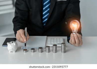 businessman holding a light bulb The idea of ​​presenting new ideas good inspiration and innovation Analyzing and recording savings data financial planning. - Shutterstock ID 2311093777