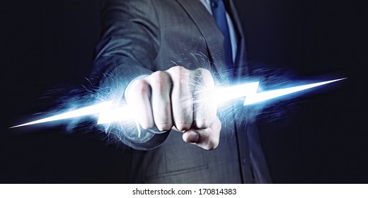 Businessman holding lightning in fist. Power and control
