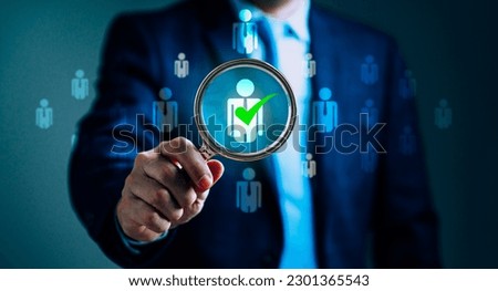 Businessman holding a magnifier, searching for human icons, human development and recruitment, emphasizes the importance of Human Resource Management in attracting the right talent for organization