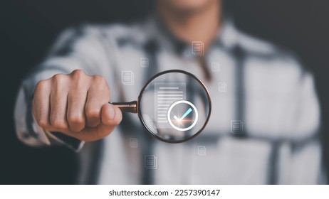 Businessman holding a magnifying glass, showing Audit Document concept,quality assessment management With a checklist, business document evaluation process, market data report analysis and consulting