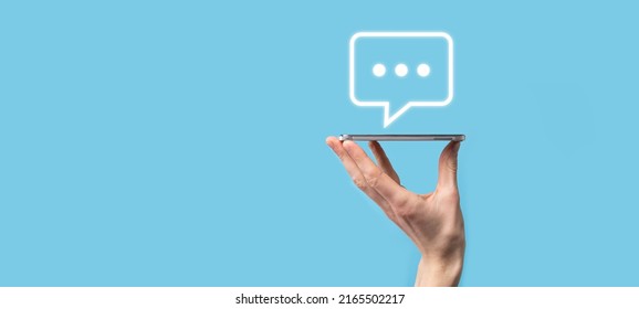 Businessman holding a message icon, bubble talk notification sign in his hands. Chat icon, sms icon, comments icon, speech bubbles. - Shutterstock ID 2165502217