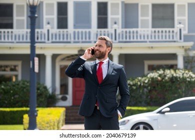 Businessman Holding Mobile Cell Phone Using App Texting Sms Message Wearing Suit. Young Urban Professional Man Using Smartphone At Home. Real Estate Agent.