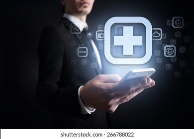 Businessman Holding A Mobile Phone With Medical App Icon On Virtual Screen. Internet Concept. Medical Concept.