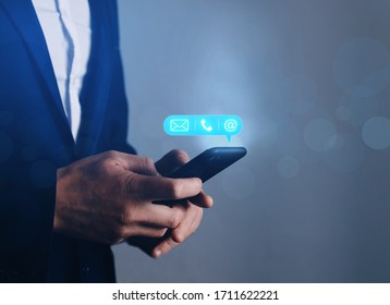 Businessman holding mobile smartphone with  mail,phone,email icon.  Custumer Support concept. - Shutterstock ID 1711622221