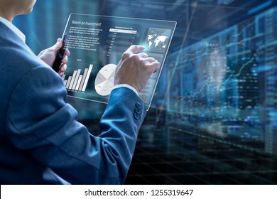 Businessman holding a modern tablet touch screen analysing on investment risk management and return on investment analysis or business performance. - Shutterstock ID 1255319647