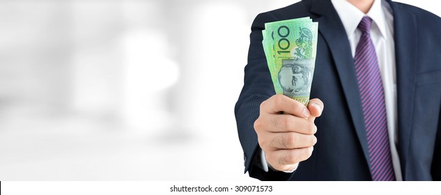Businessman holding money, Australian dollar (AUD) banknotes, in his fist - business and financial panoramic header background