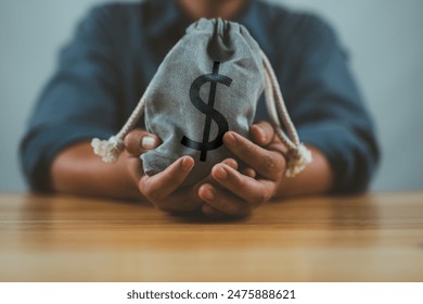 Businessman holding money bag with USD dollar sign for give dividend return profit from investment funding and stock market , Financial and accounting concept. - Powered by Shutterstock