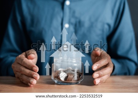 Businessman holding a money jar with a house inside to make a profit on interest real estate investment growth value, home interest rate, inflation, planning future inflation and passive income.