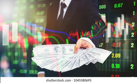 Businessman Holding Money US Dollar Bills On Digital Stock Market Financial Exchange Information And Trading Graph Background