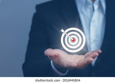 businessman holding out his hand On the hand there is a target icon of a board and a dart. Goal Setting Ideas, Objectives and Investment Goal Ideas.