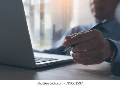 Businessman holding pen leaning on chair working and concentrate looking at laptop computer screen in office. Business strategy analysis, review report, planning new project, startup business concept.