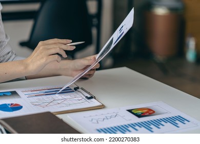 Businessman Holding Pen And Pie Chart Document Showing Company Financial Data He Sits In A Private Office With A Laptop Analyzing Financial Data In Chart Form. Financial Concept