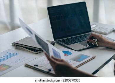 Businessman Holding Pen And Pie Chart Document Showing Company Financial Data He Sits In A Private Office With A Laptop Analyzing Financial Data In Chart Form. Financial Concept