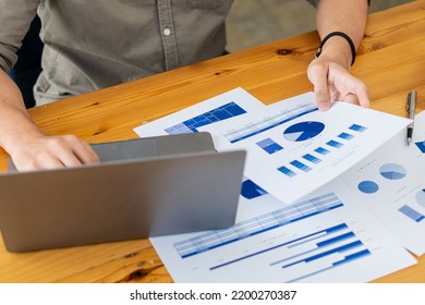 Businessman Holding Pen And Pie Chart Document Showing Company Financial Data He Sits In A Private Office With A Laptop Analyzing Financial Data In Chart Form. Financial Concept