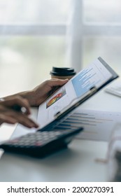 Businessman Holding Pen And Pie Chart Document Showing Company Financial Data He Sits In A Private Office With A Laptop Analyzing Financial Data In Chart Form. Financial Concept