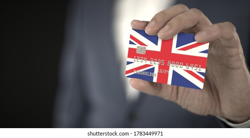 Businessman holding plastic bank card with printed flag of the United Kingdom, fictional numbers - Shutterstock ID 1783449971