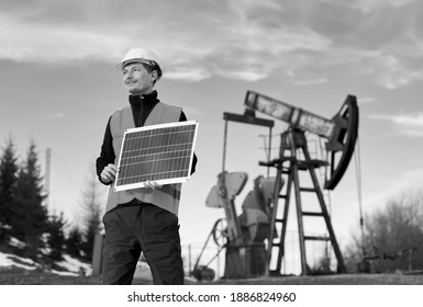 Homme d'affaires tenant un panneau solaire portable. Travailleur debout sur le territoire d'un champ pétrolier avec prise de pompe sur fond noir. Concept de l'industrie pétrolière et des sources d'énergie alternatives. Image en noir et blanc