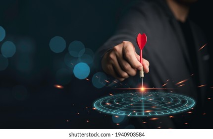 Businessman holding red arrow dart throwing to virtual dartboard on blue bokeh background and copy space, business achievement objective target concept. - Shutterstock ID 1940903584