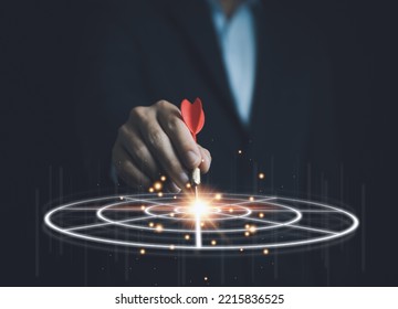 Businessman holding a red dart aiming precisely at the center of the digital technology target board. business investment objective concept Marketing strategies and goals for success - Shutterstock ID 2215836525
