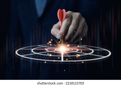 Businessman holding a red dart aiming precisely at the center of the digital technology target board. business investment objective concept Marketing strategies and goals for success - Shutterstock ID 2218115703