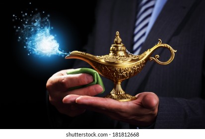 Businessman holding and rubbing a magic Aladdins genie lamp concept for business aspirations, hope and wishes